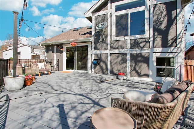 back of property with a deck, fence, a shingled roof, and an outdoor hangout area