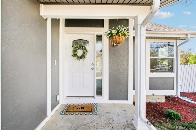 entrance to property with roof with shingles and stucco siding