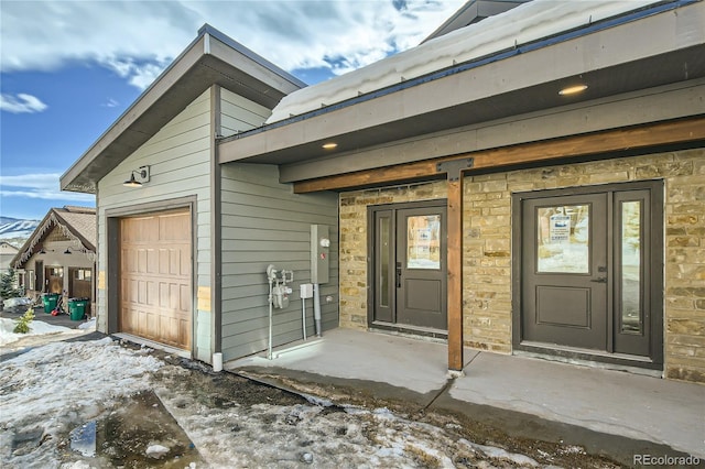 view of exterior entry featuring a garage and stone siding