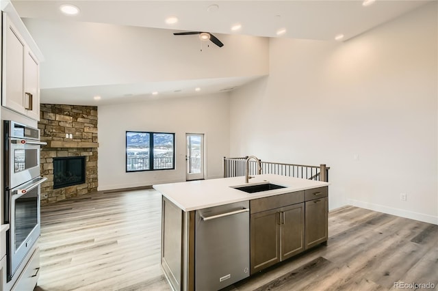 kitchen featuring lofted ceiling, a sink, open floor plan, appliances with stainless steel finishes, and light wood-type flooring