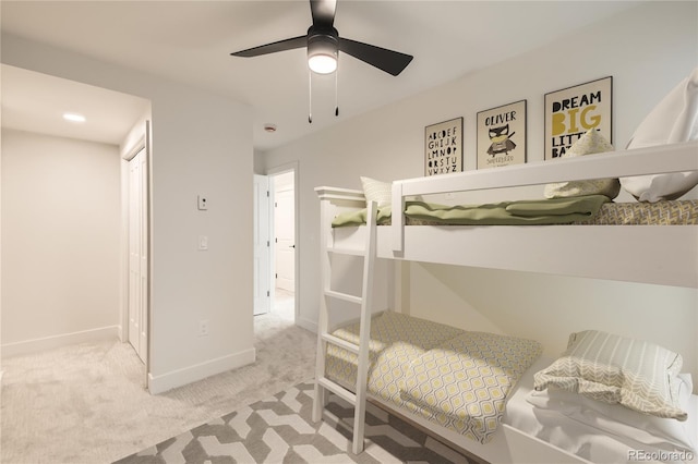 carpeted bedroom with ceiling fan, a closet, and baseboards