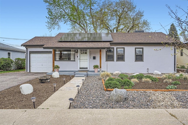 single story home with a garage, roof with shingles, and stucco siding