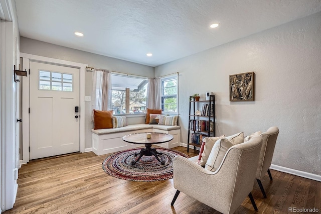 living area featuring baseboards, recessed lighting, a textured wall, and wood finished floors