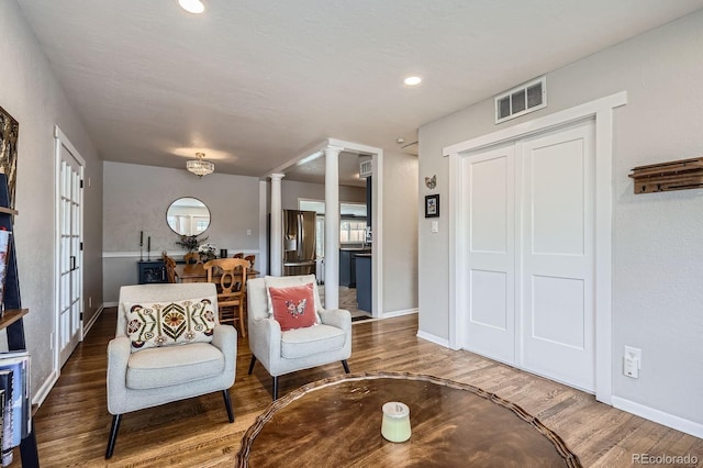 living area featuring recessed lighting, baseboards, wood finished floors, ornate columns, and visible vents
