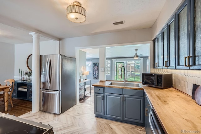 kitchen featuring wood counters, appliances with stainless steel finishes, a sink, and visible vents