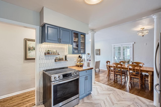 kitchen with glass insert cabinets, ornate columns, blue cabinets, wood counters, and stainless steel range with electric cooktop