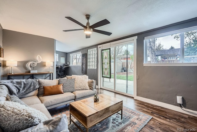 living room with ceiling fan, a textured wall, baseboards, wood finished floors, and lofted ceiling