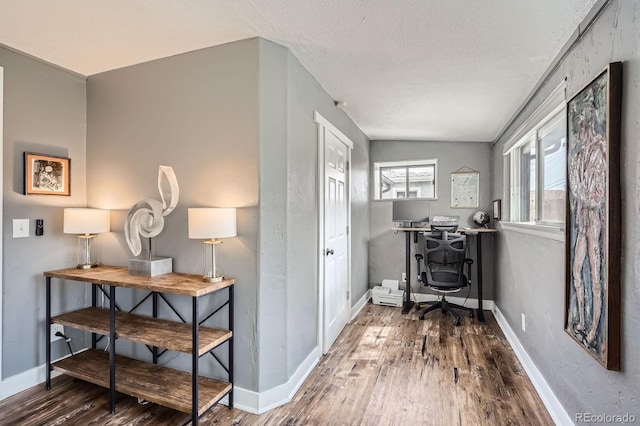 hallway featuring baseboards, a textured ceiling, and wood finished floors