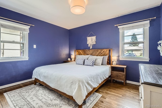bedroom with baseboards, multiple windows, and wood finished floors