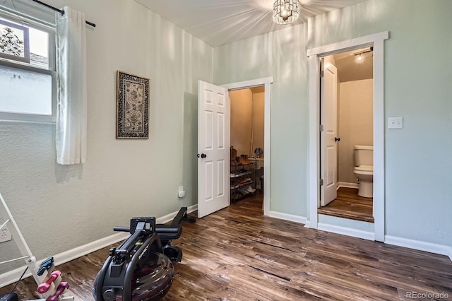 unfurnished bedroom with baseboards, dark wood-style flooring, and ensuite bath