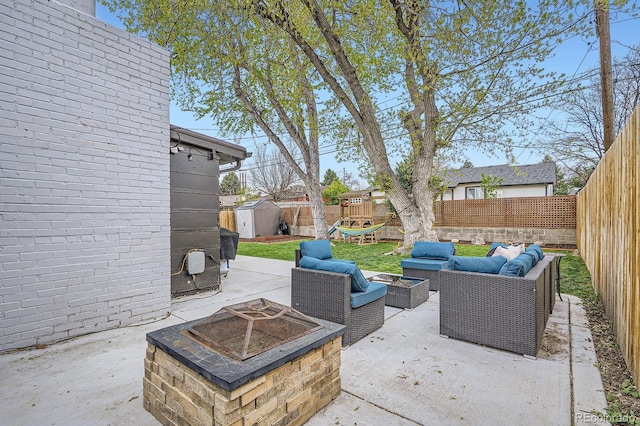 view of patio featuring an outdoor structure, a shed, a fenced backyard, and an outdoor living space with a fire pit