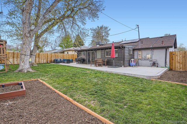 rear view of house featuring a garden, a patio, a fenced backyard, roof mounted solar panels, and a lawn