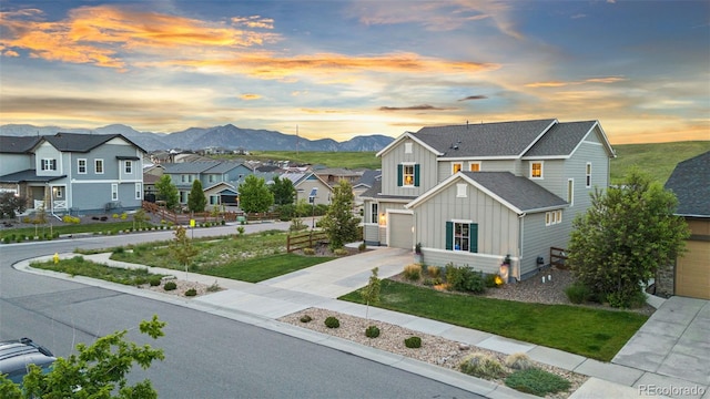 17335 W 94th Ave, Arvada, CO 80007 - view of front of house with board and batten siding, concrete driveway, a residential view, a mountain view, and a front yard
