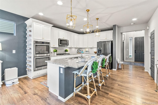 17335 W 94th Ave, Arvada, CO 80007 - kitchen featuring appliances with stainless steel finishes, a sink, recessed lighting, white cabinetry, and a kitchen island with sink