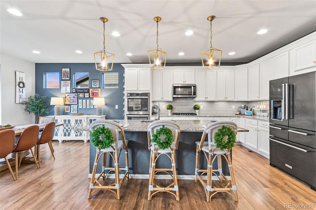 17335 W 94th Ave, Arvada, CO 80007 - kitchen featuring stainless steel appliances, recessed lighting, tasteful backsplash, a center island with sink, and white cabinetry