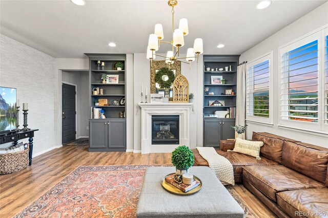 17335 W 94th Ave, Arvada, CO 80007 - living area featuring a chandelier, light wood-style flooring, a glass covered fireplace, recessed lighting, and built in features