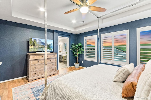 17335 W 94th Ave, Arvada, CO 80007 - bedroom with wood finished floors, a tray ceiling, baseboards, ensuite bathroom, and ceiling fan