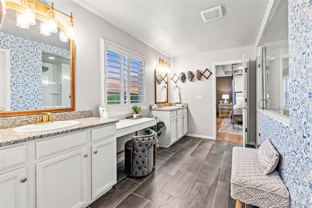 17335 W 94th Ave, Arvada, CO 80007 - bathroom featuring connected bathroom, two vanities, a shower stall, a textured ceiling, and wood finish floors