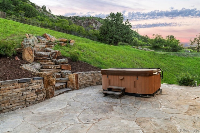 patio terrace at dusk featuring a hot tub