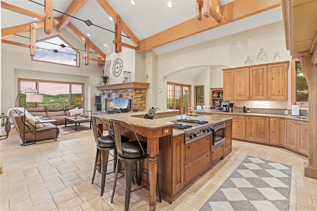 kitchen featuring a kitchen island, appliances with stainless steel finishes, high vaulted ceiling, beamed ceiling, and a healthy amount of sunlight