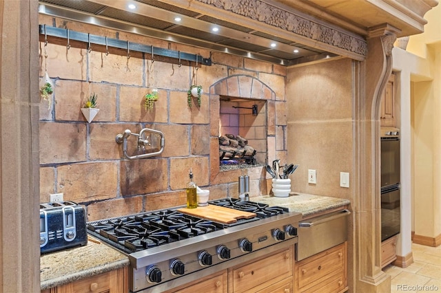 kitchen featuring light stone counters, stainless steel gas cooktop, and custom range hood