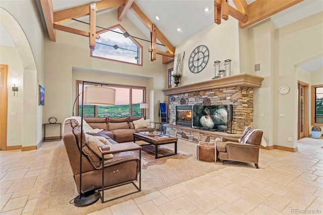 living room featuring a stone fireplace, high vaulted ceiling, and beamed ceiling