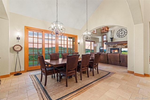 dining space with plenty of natural light, high vaulted ceiling, a fireplace, and an inviting chandelier