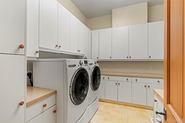 washroom with cabinets and washing machine and clothes dryer