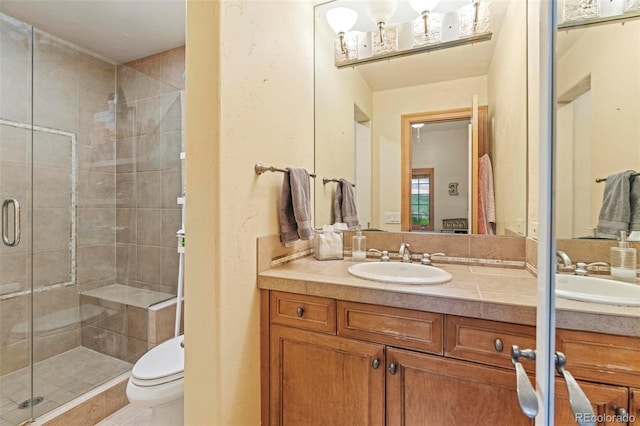 bathroom featuring a shower with door, vanity, and toilet