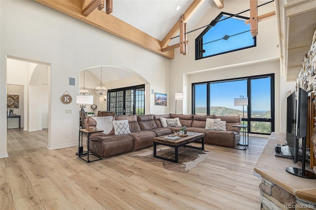 12963 Silver Elk Ln, Littleton, CO 80127 - living room featuring arched walkways, high vaulted ceiling, light wood-style floors, beamed ceiling, and baseboards