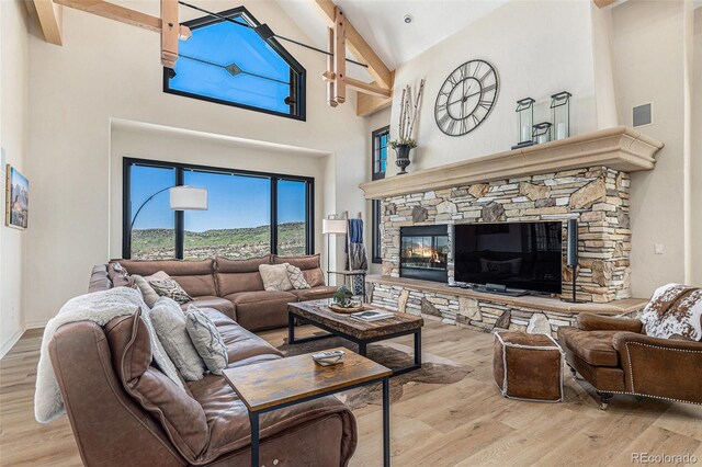 12963 Silver Elk Ln, Littleton, CO 80127 - living room with high vaulted ceiling, wood finished floors, a stone fireplace, beamed ceiling, and baseboards