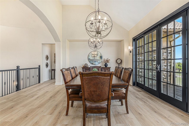 12963 Silver Elk Ln, Littleton, CO 80127 - dining area with a chandelier, light wood-type flooring, arched walkways, plenty of natural light, and high vaulted ceiling