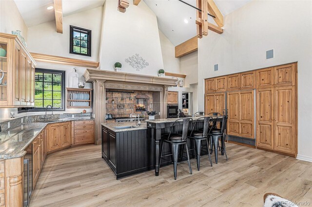 12963 Silver Elk Ln, Littleton, CO 80127 - kitchen with high vaulted ceiling, a large island with sink, a sink, light wood finished floors, and light stone counters