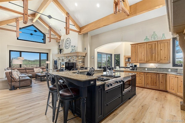 12963 Silver Elk Ln, Littleton, CO 80127 - kitchen featuring high vaulted ceiling, light wood finished floors, arched walkways, a kitchen breakfast bar, and light stone counters