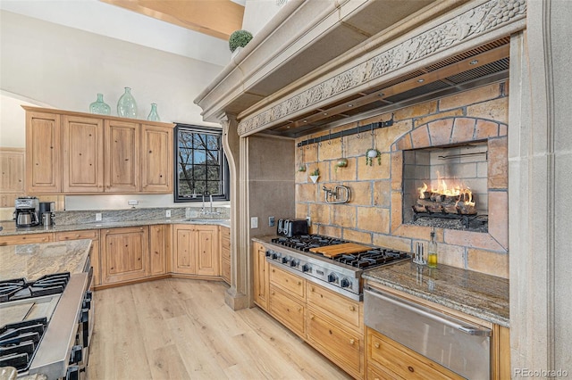 12963 Silver Elk Ln, Littleton, CO 80127 - kitchen with a warming drawer, stainless steel appliances, a sink, light brown cabinetry, and custom exhaust hood