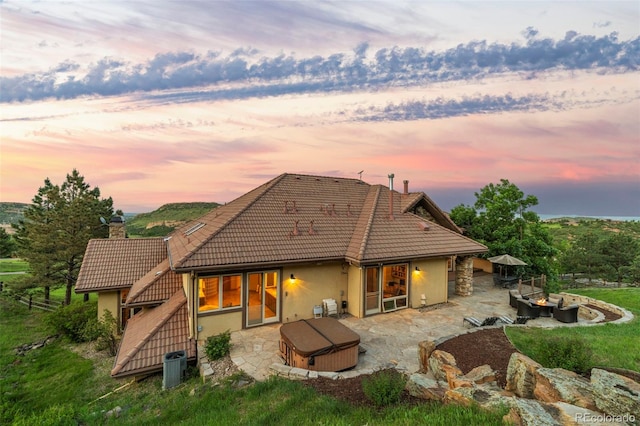 12963 Silver Elk Ln, Littleton, CO 80127 - rear view of property with a hot tub, stucco siding, a tiled roof, a patio area, and central AC