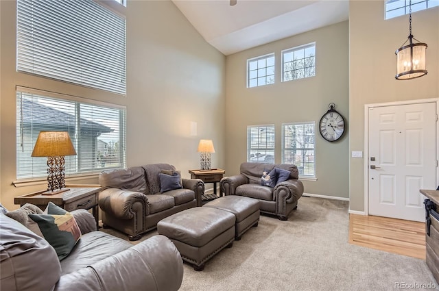 living room with high vaulted ceiling, a chandelier, light carpet, and baseboards