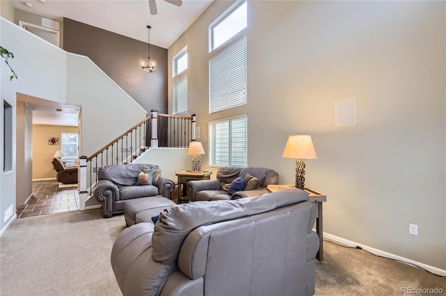 living room with baseboards, carpet flooring, stairs, and a towering ceiling
