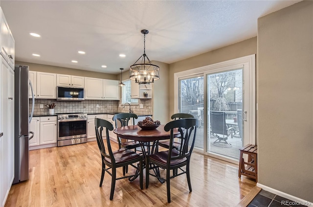 dining area with light wood-style floors, baseboards, an inviting chandelier, and recessed lighting