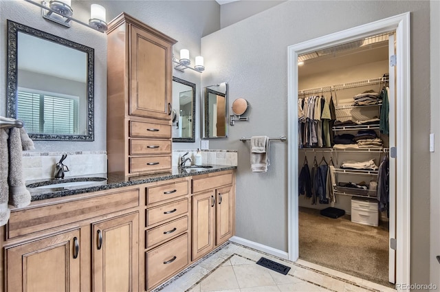 bathroom featuring a sink, tile patterned floors, double vanity, and a spacious closet