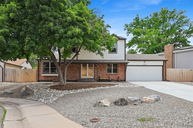 10378 W Weaver Ave, Littleton, CO 80127 - view of front facade with an attached garage, concrete driveway, brick siding, and a porch