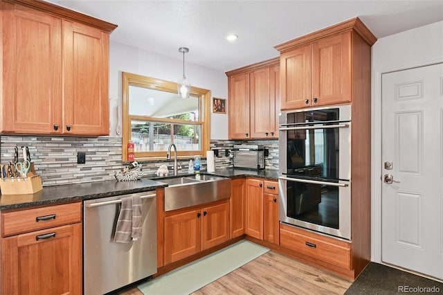 10378 W Weaver Ave, Littleton, CO 80127 - kitchen with appliances with stainless steel finishes, tasteful backsplash, light wood-style flooring, dark stone counters, and recessed lighting