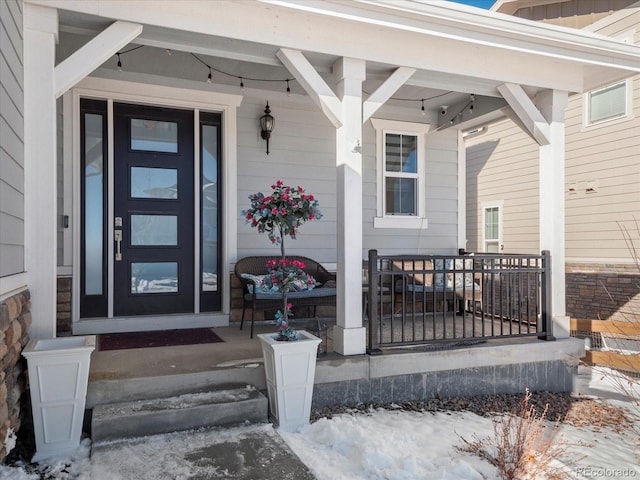 snow covered property entrance featuring a porch