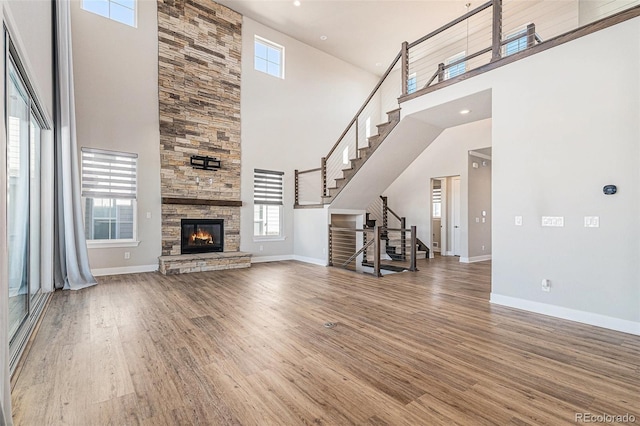 unfurnished living room featuring hardwood / wood-style floors, a stone fireplace, and plenty of natural light