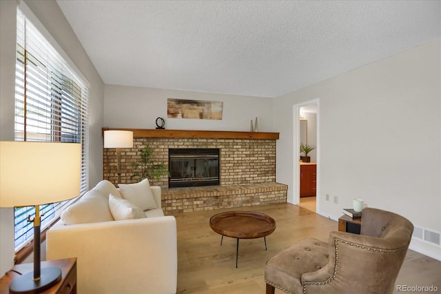12089 W Burgundy Ave, Littleton, CO 80127 - living area featuring wood finished floors, a textured ceiling, and a brick fireplace