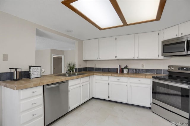 12089 W Burgundy Ave, Littleton, CO 80127 - kitchen featuring stainless steel appliances, white cabinets, a peninsula, and light tile patterned floors