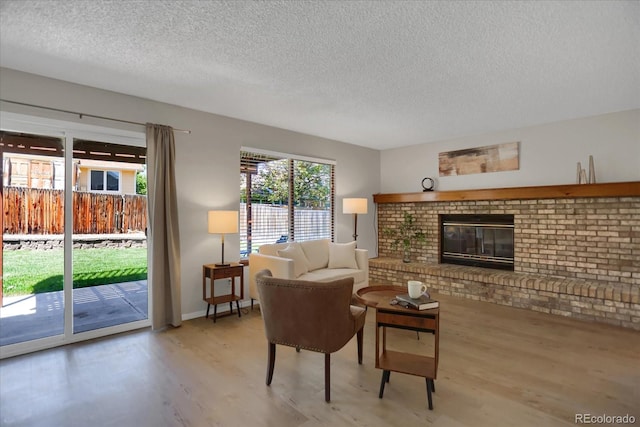 12089 W Burgundy Ave, Littleton, CO 80127 - living room featuring light wood-type flooring, a textured ceiling, and a brick fireplace