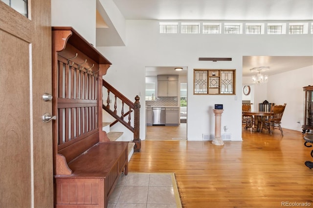 foyer featuring stairway, a chandelier, light wood-style flooring, and a wealth of natural light