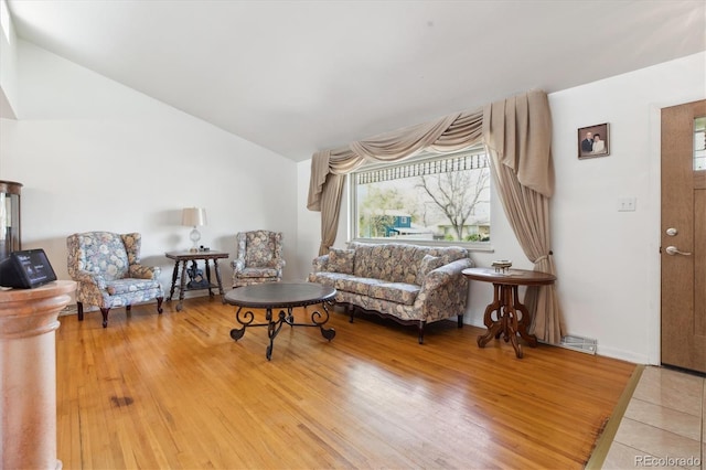 living room with lofted ceiling, wood finished floors, plenty of natural light, and visible vents