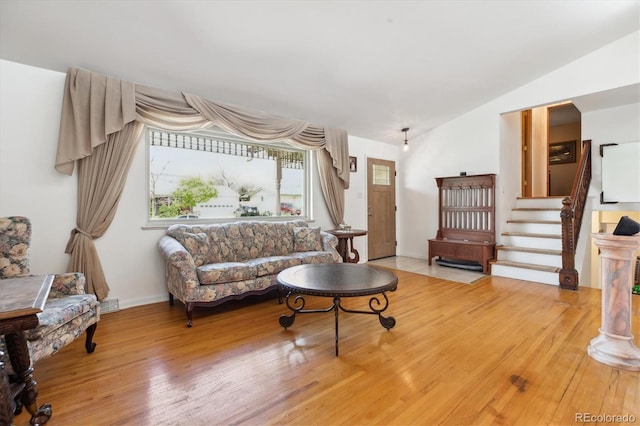 living room with lofted ceiling, baseboards, visible vents, wood finished floors, and stairway